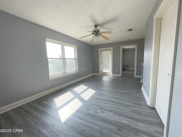 interior space featuring dark wood-style flooring, a closet, visible vents, a textured ceiling, and baseboards