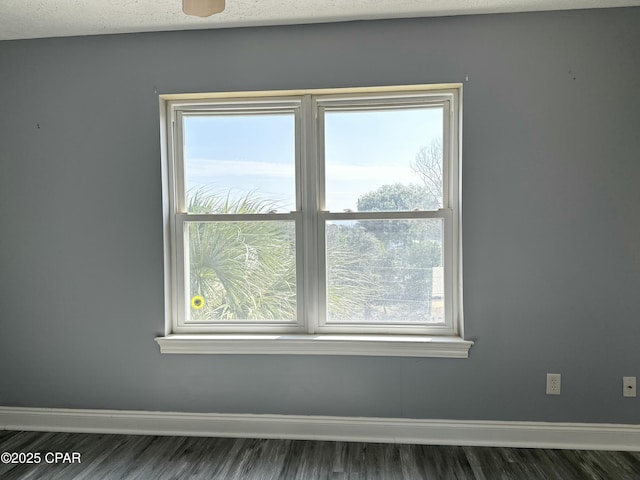 unfurnished room featuring dark wood-style floors, a textured ceiling, baseboards, and a wealth of natural light