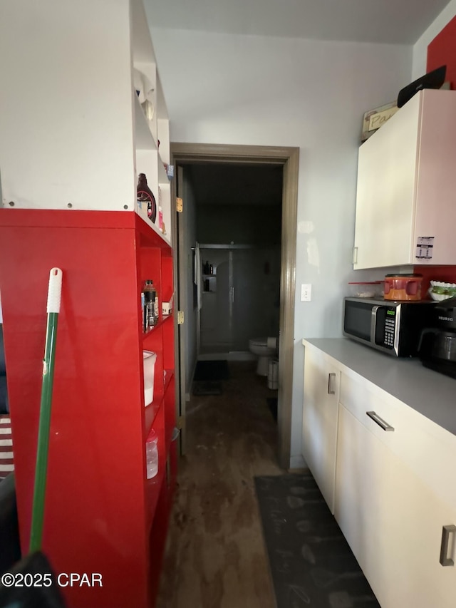 kitchen with light countertops, white cabinetry, stainless steel microwave, and concrete floors