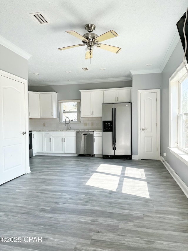 kitchen with stainless steel appliances, light countertops, backsplash, white cabinets, and a sink