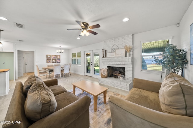 living room with light wood-type flooring, plenty of natural light, visible vents, and a brick fireplace