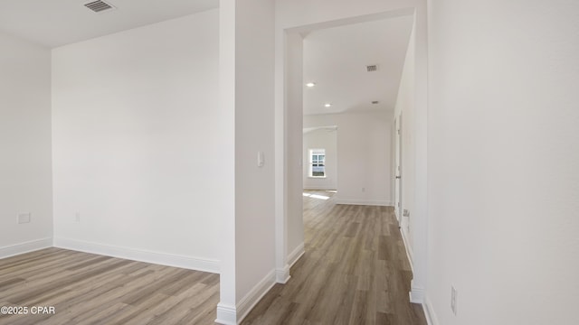 corridor featuring visible vents, baseboards, and wood finished floors