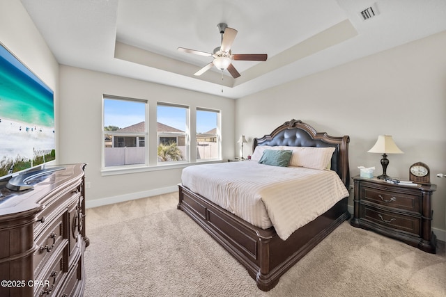 bedroom featuring a raised ceiling, visible vents, light carpet, and baseboards