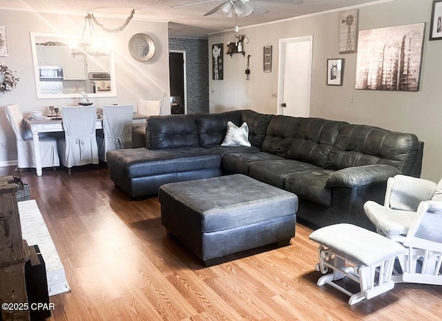 living area featuring ceiling fan, crown molding, and wood finished floors