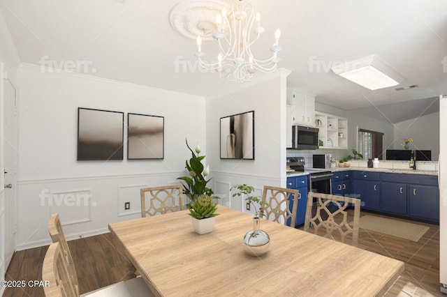 dining area with a chandelier, wood finished floors, visible vents, and a decorative wall