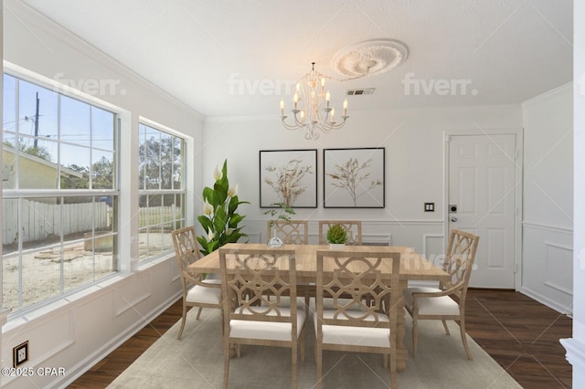 dining room featuring crown molding, dark wood-style flooring, and a decorative wall