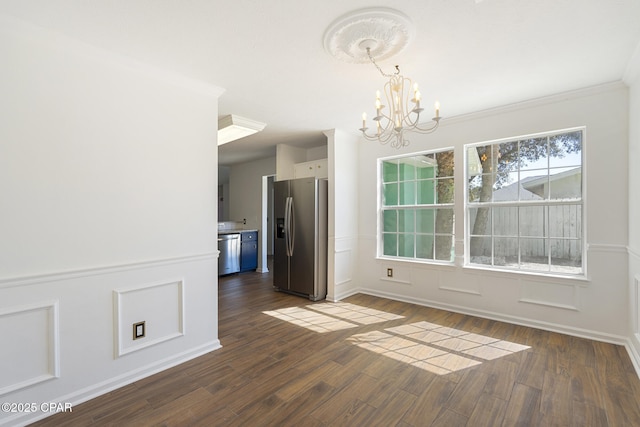 unfurnished dining area with ornamental molding, a decorative wall, dark wood finished floors, and a notable chandelier