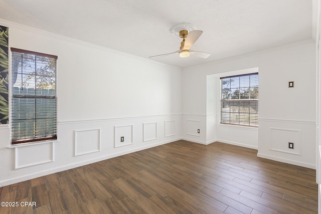 spare room with a textured ceiling, ornamental molding, dark wood-style flooring, and a ceiling fan