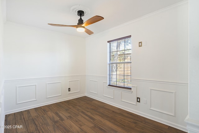 spare room featuring dark wood-style floors, ceiling fan, ornamental molding, and wainscoting