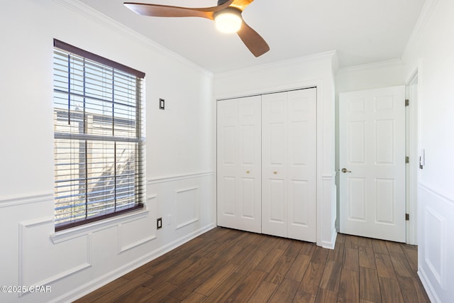 unfurnished bedroom featuring a closet, ornamental molding, a decorative wall, and dark wood-type flooring