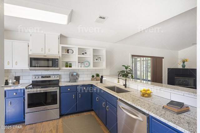 kitchen with stainless steel appliances, visible vents, decorative backsplash, a sink, and blue cabinets