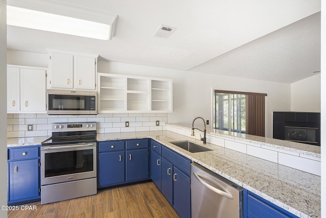 kitchen with stainless steel appliances, a sink, visible vents, blue cabinetry, and open shelves