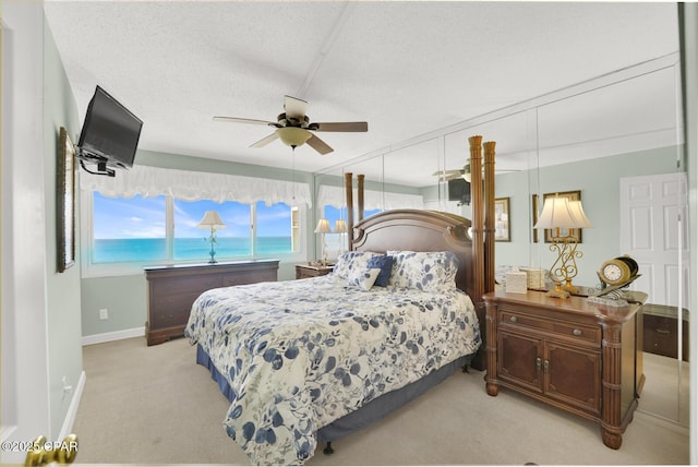 bedroom featuring ceiling fan, baseboards, a textured ceiling, and light colored carpet