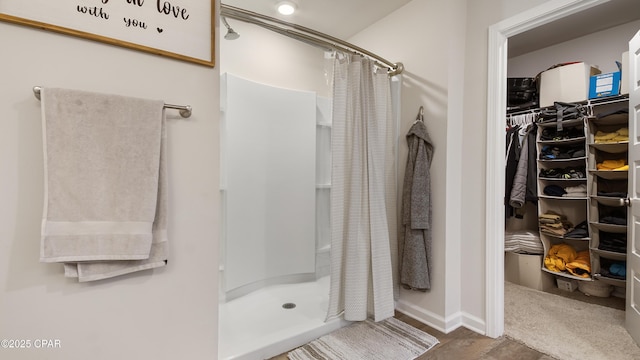 bathroom featuring a stall shower, a walk in closet, and baseboards