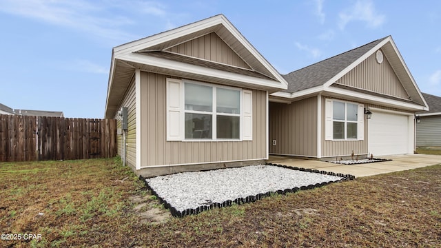 view of front of house with an attached garage, a shingled roof, fence, and a front lawn