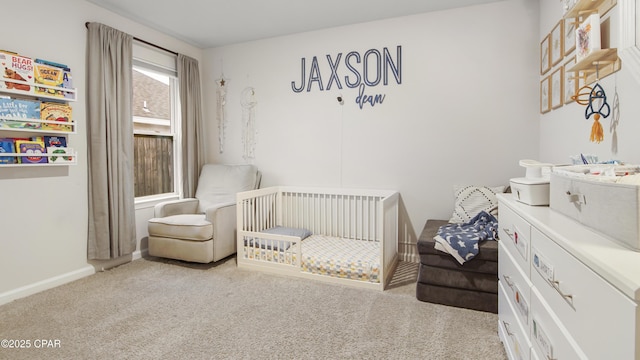 bedroom with a nursery area, light carpet, and baseboards