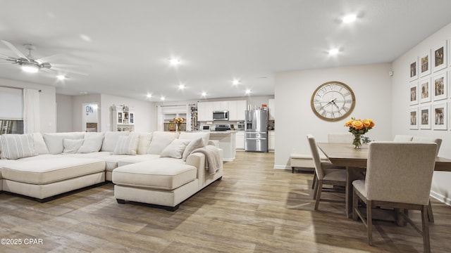 living area featuring wood finished floors, a ceiling fan, and recessed lighting