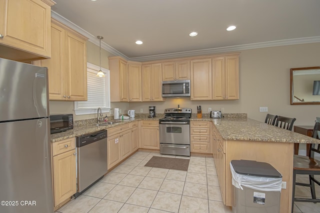 kitchen with light brown cabinets, stainless steel appliances, a peninsula, a sink, and a kitchen breakfast bar