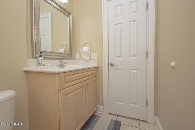 half bathroom with toilet, tile patterned flooring, baseboards, and vanity