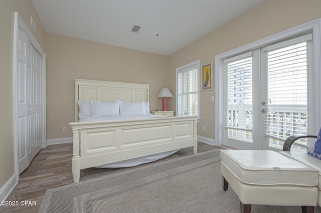 bedroom featuring access to outside, baseboards, wood finished floors, and french doors