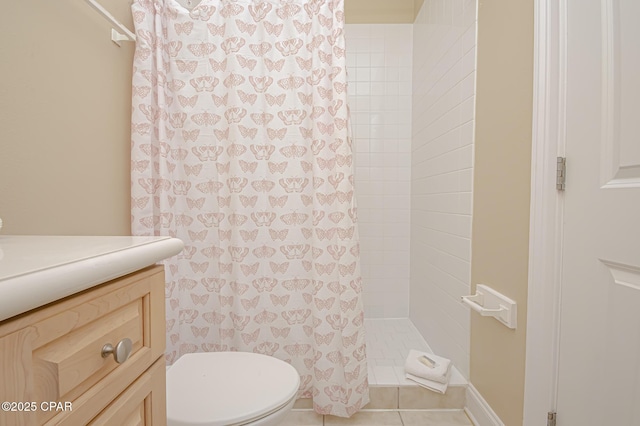 bathroom featuring toilet, tile patterned floors, tiled shower, and vanity