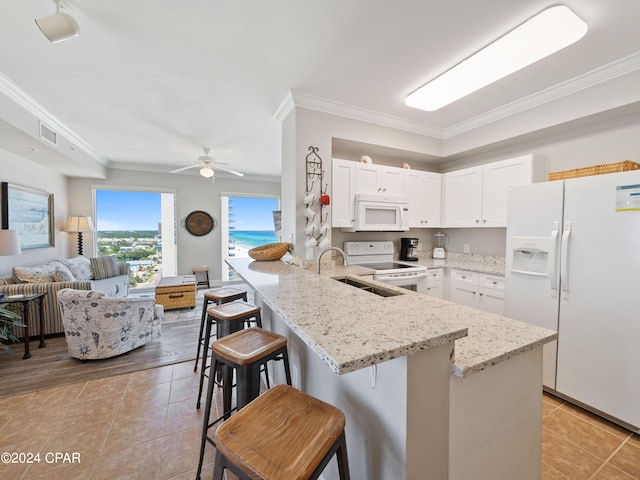 kitchen featuring open floor plan, white cabinetry, white appliances, a peninsula, and a kitchen bar