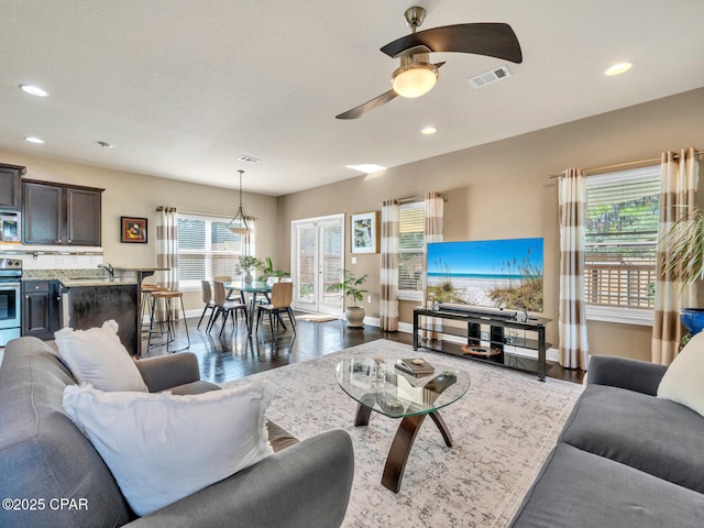 living room featuring a ceiling fan, recessed lighting, visible vents, and wood finished floors