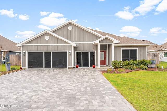 single story home with decorative driveway, roof with shingles, an attached garage, board and batten siding, and a front lawn