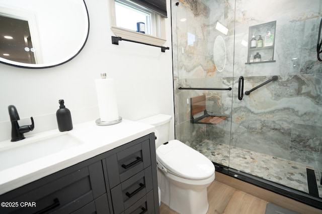 bathroom featuring vanity, wood finished floors, a marble finish shower, and toilet