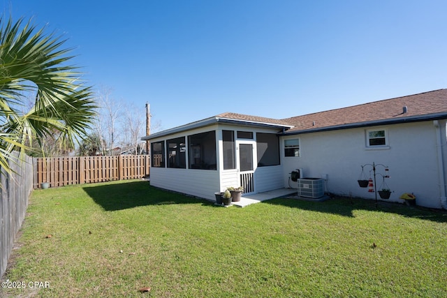 rear view of property with a fenced backyard, central AC, a sunroom, a yard, and stucco siding