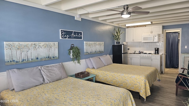 bedroom featuring beamed ceiling, wood finished floors, freestanding refrigerator, and a ceiling fan