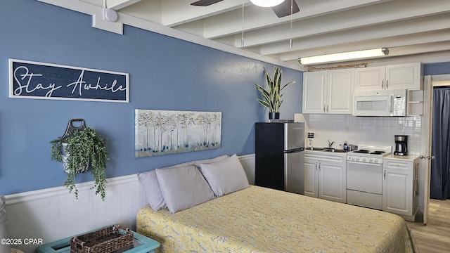 bedroom with light wood-style flooring, beam ceiling, a sink, and freestanding refrigerator