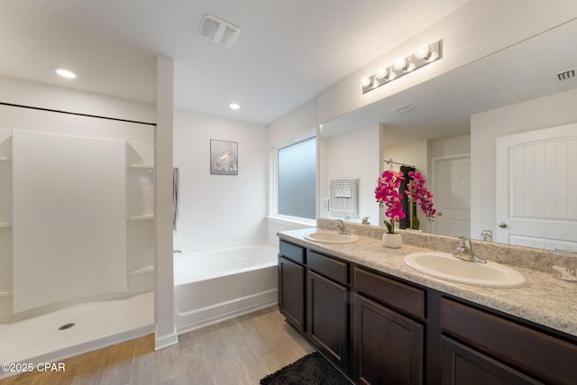 full bath with walk in shower, a bath, a sink, and wood finished floors