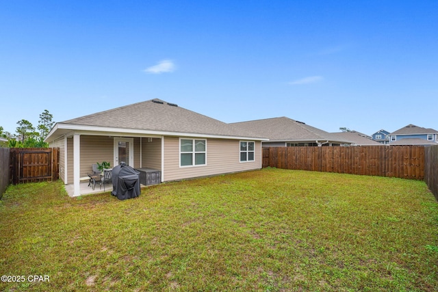 rear view of property with a patio area, a fenced backyard, a shingled roof, and a lawn
