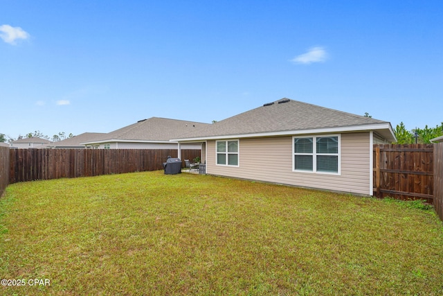 back of house featuring a shingled roof, a yard, and a fenced backyard
