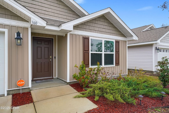 property entrance with board and batten siding and a shingled roof
