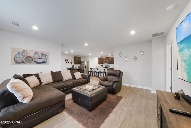 living area with recessed lighting, visible vents, and light wood-type flooring