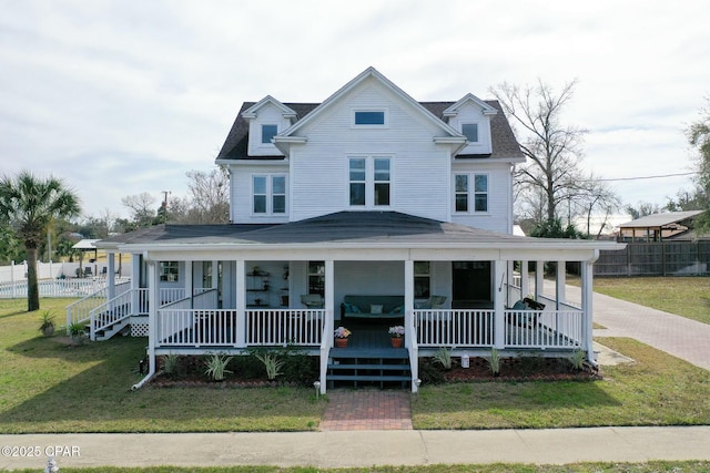 farmhouse featuring a porch, fence, and a front lawn