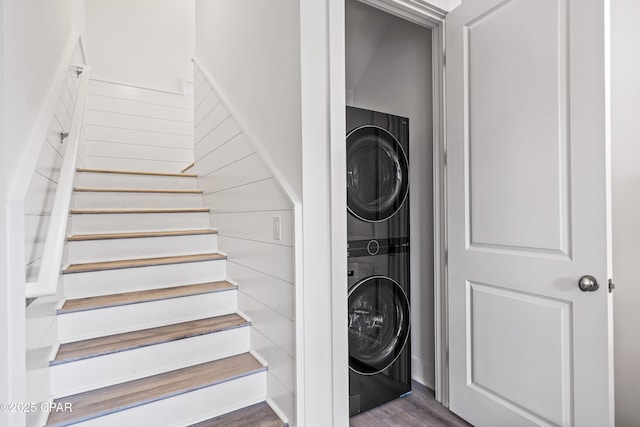 staircase with stacked washer / dryer and wood finished floors