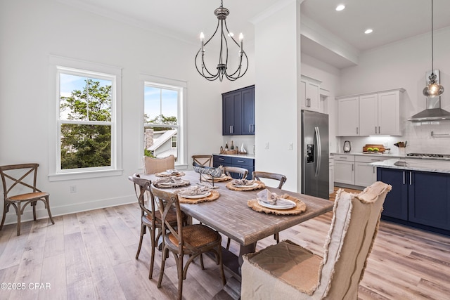 dining space with a notable chandelier, a high ceiling, light wood-style floors, baseboards, and crown molding