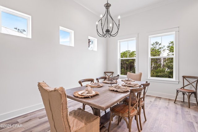 dining space with light wood-type flooring, a notable chandelier, and baseboards