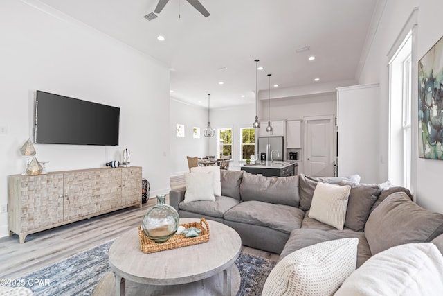 living room featuring ceiling fan, light wood-style flooring, recessed lighting, baseboards, and crown molding