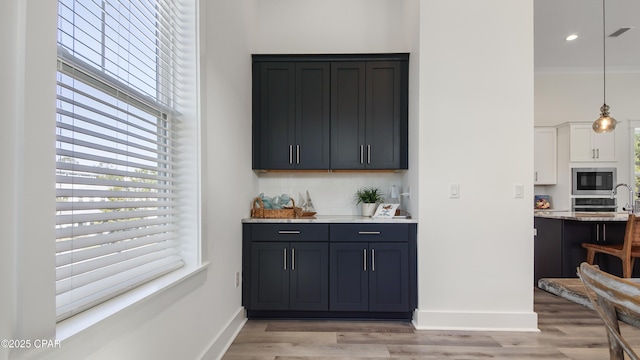 150 Grande Pointe Cir, Inlet Beach, FL 32461 - indoor wet bar featuring stainless steel microwave, backsplash, healthy amount of natural light, light wood-type flooring, and ornamental molding