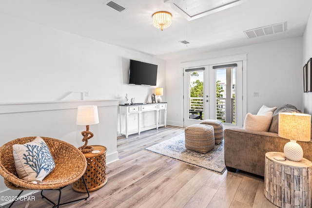 living area featuring french doors, light wood-style floors, visible vents, and attic access