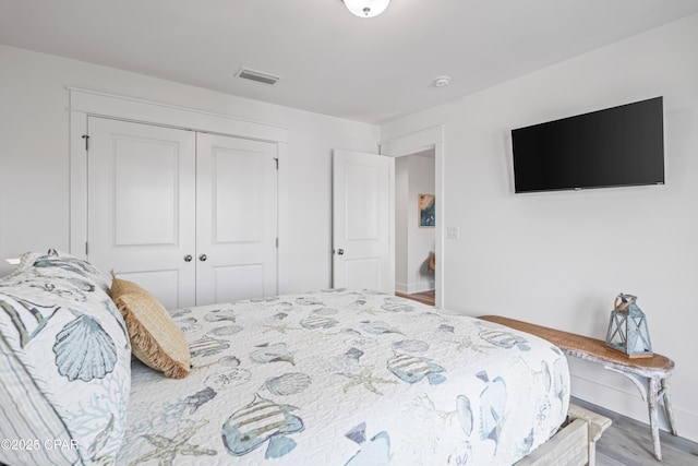 bedroom featuring baseboards, visible vents, a closet, and wood finished floors