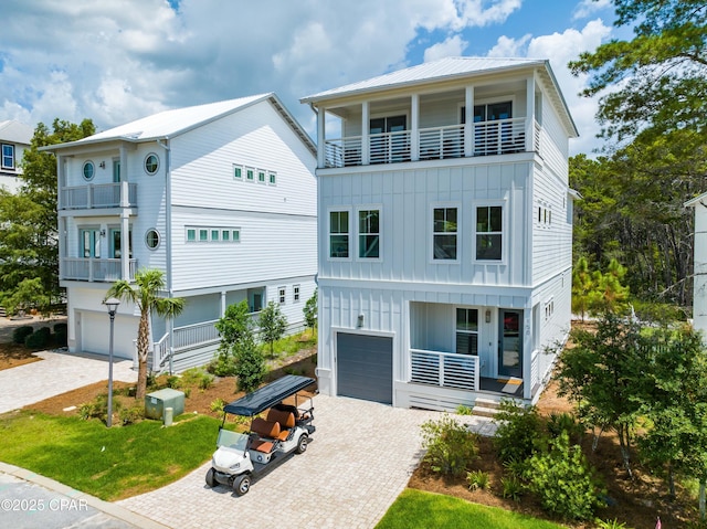 view of front of house with board and batten siding, decorative driveway, and a balcony