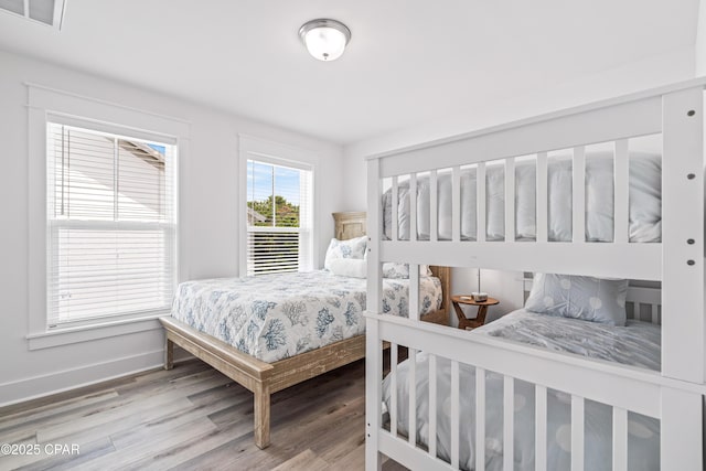 bedroom with visible vents, baseboards, and wood finished floors