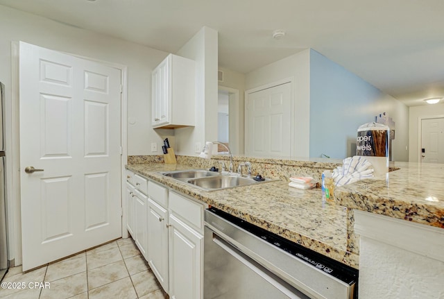 kitchen featuring a sink, stainless steel dishwasher, light tile patterned flooring, and white cabinets
