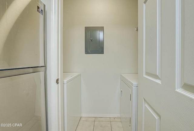 washroom featuring washing machine and clothes dryer, electric panel, light tile patterned floors, and baseboards