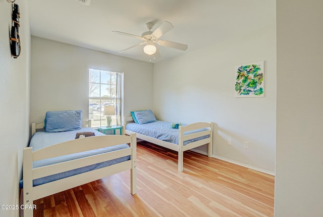 bedroom featuring wood finished floors, baseboards, and ceiling fan